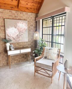 A side view of the room featuring an old wooden chair and table, adorned with paintings, vases, plants, and light. Property styling by Sell in Style, Brisbane.